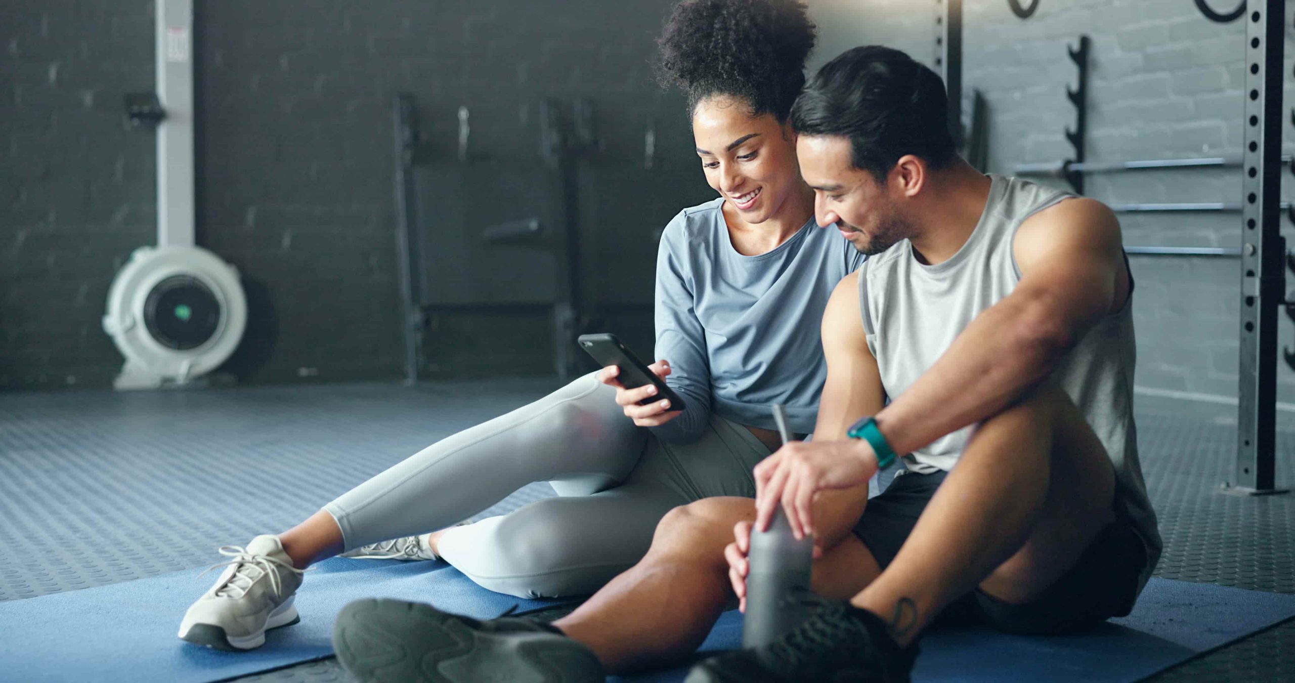 Couple at the gym looking at a phone